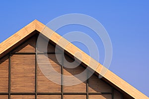 Part of vintage wooden gable roof with battens decoration against blue clear sky background