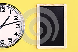 Part of wall clock and black notice board on yellow background