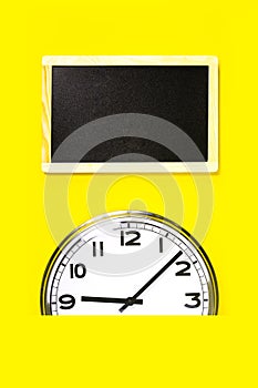 Part of wall clock and black notice board on yellow background