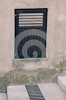 Part of the wall of an old house with ventilation grille and guttering