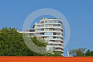 Part of a white big house with balconies on a background of blue sky