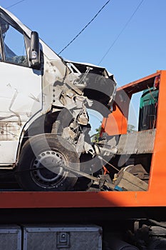 part of a white broken passenger car after an accident stands on the orange metal of a tow truck