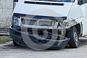 Part of the white bus after the accident with a broken bumper and headlight on the road