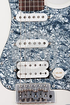 Part of white electric guitar, studio shoot.  2 x Single Coil and 1 x Humbucking. Black Pearl pickguard, Rosewood Fingerboard