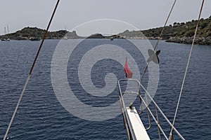 Part of the yacht ladder, red flag on board. blue sea