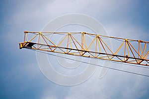 Part of a yellow construction crane and a blue sky is close up