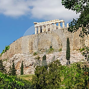 Parthenon famous temple on acropolis fortified hill and vibrant green foliage.