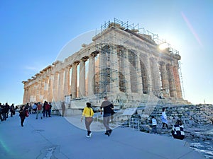 Photo of the morning sun rising over the majestic Parthenon temple on top of the Acropolis hill in Athens, Greece.