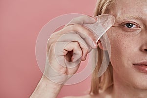 Partial of caucasian guy apply ice slice on face