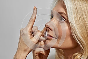 Partial image of woman putting contact lens in eye