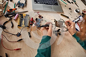 Partial male engineer soldering microchip at table
