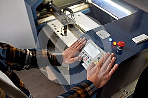 Partial male worker pressing button on CNC machine