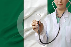Partial photo of a doctorâ€™s girl, a nurse with a stethoscope in uniform against the background of the national flag of the state
