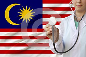 Partial photo of a girl doctor, nurse with a stethoscope in uniform against the background of the national flag of the state of