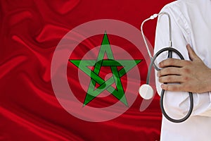 Partial photograph of a doctor with a stethoscope in a professional medical uniform against the background of the national flag of