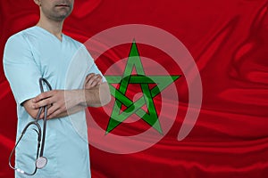 Partial photograph of a doctor with a stethoscope in a professional medical uniform against the background of the national flag of