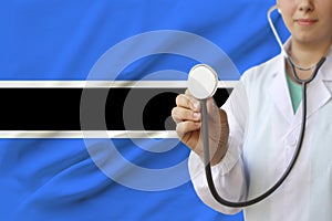 Partial photograph of a doctorâ€™s girl, a nurse with a stethoscope in uniform against the background of the colored national flag