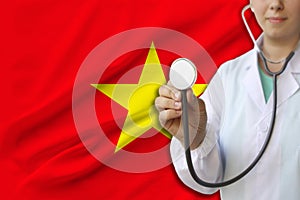 Partial photograph of a doctorâ€™s girl, a nurse with a stethoscope in uniform against the background of the colored national flag