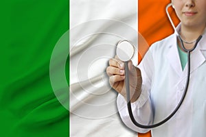 Partial photograph of a doctorâ€™s girl, a nurse with a stethoscope in uniform against the background of the colored national flag