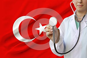 Partial photograph of a doctorâ€™s girl, a nurse with a stethoscope in uniform against the background of the colored national flag