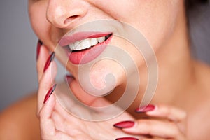 Partial portrait of woman smiling with red manicure and flawless complexion