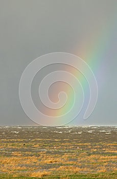 Partial rainbow over sea on wet windy day