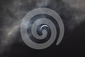 Partial solar eclipse - moon covers sun, dark clouds, celestial drama - crescent sun - atmospheric mood