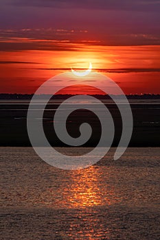 Partial solar eclipse with a reflection in water.