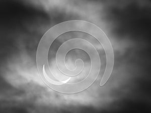 Partial solar eclipse with sun through clouds