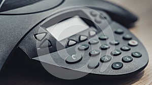 partial of speakerphone on wooden table