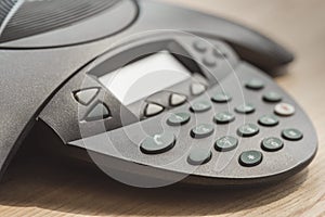 partial of speakerphone on wooden table