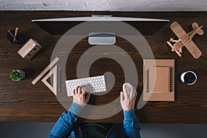 partial top view of person typing on keyboard and using desktop computer