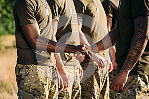 partial view of african american soldier and tactical instructor in military uniform shaking hands