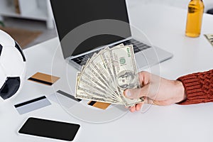 partial view of bookmaker holding dollars