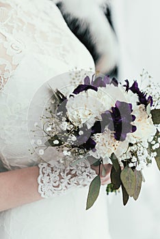 partial view of bride in white dress with beautiful bridal bouquet