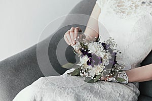 partial view of bride in white dress with beautiful bridal bouquet resting