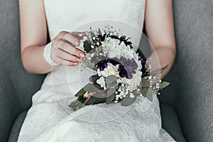 partial view of bride in white dress with beautiful bridal bouquet resting