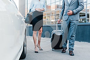 partial view of business people with luggage walking to car