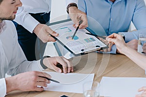 partial view of business people working on business plan at workplace