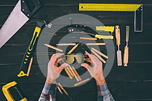 partial view of carpenter holding goggles in hands with various industrial tools around