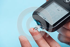 Partial view of female fingers testing glucose level with glucometer isolated