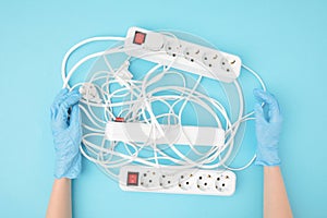 Partial view of female hands in protective gloves and extension cords