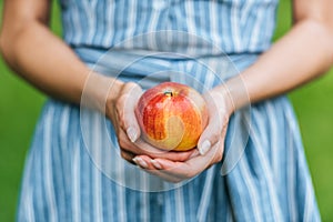 partial view of girl holding one ripe apple