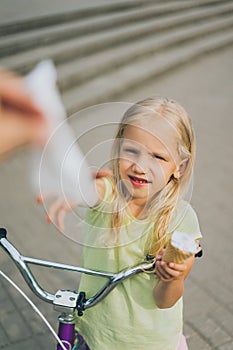 partial view of girl with ice cream taking napkin from someone