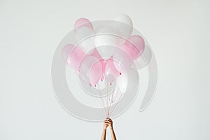 partial view of hands holding bunch of pink and white balloons