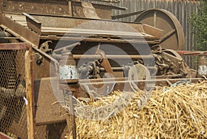 Partial view of a historic threshing machine in operation with a straw ball in the foreground