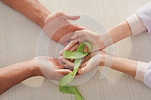 partial view of male and female hands with green ribbon - mental