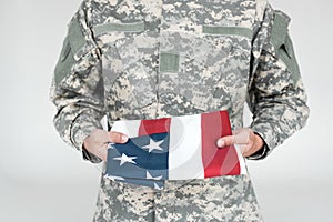 partial view of male soldier in military uniform with american flag in hands