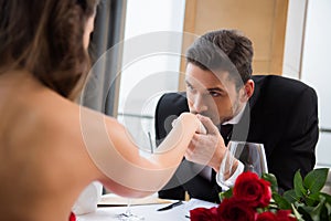 partial view of man kissing girlfirend hand on romantic date in restaurant, st valentine day