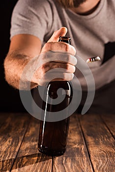 partial view of man opening beer bottle at wooden